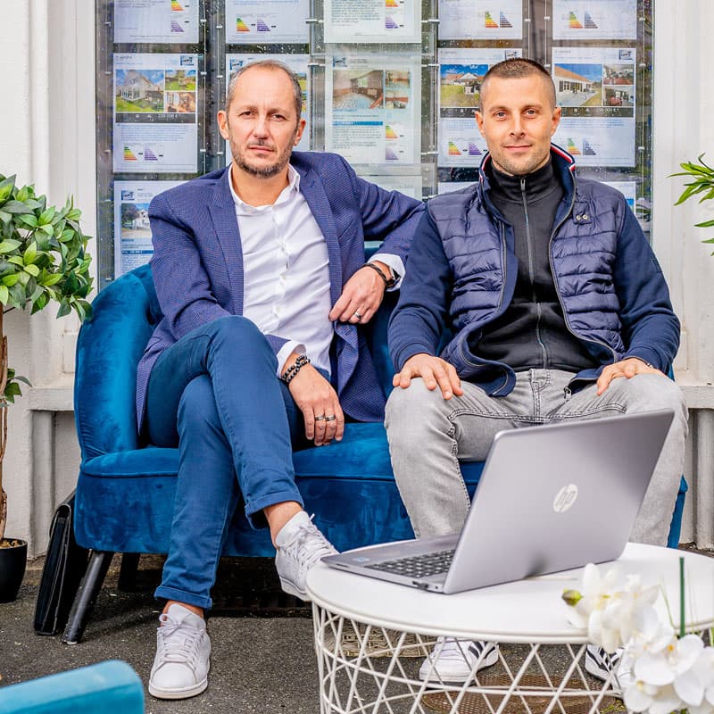 Deux professionnels de l'immobilier devant leur agence