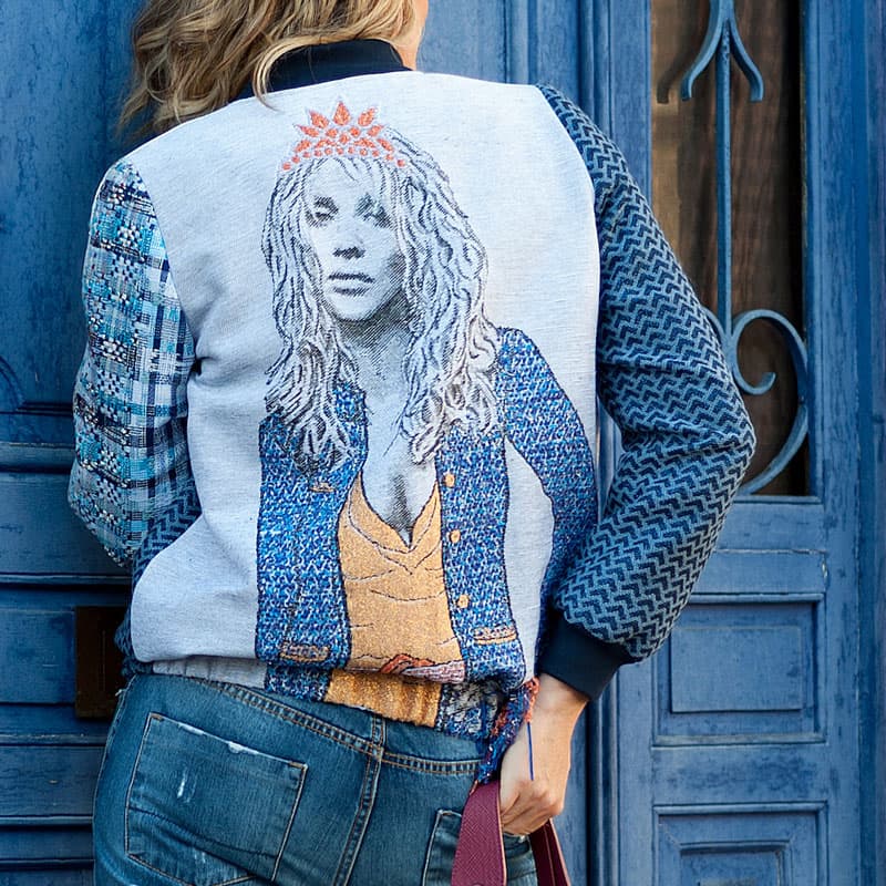 Femme portant une veste brodée artistique devant une porte bleue